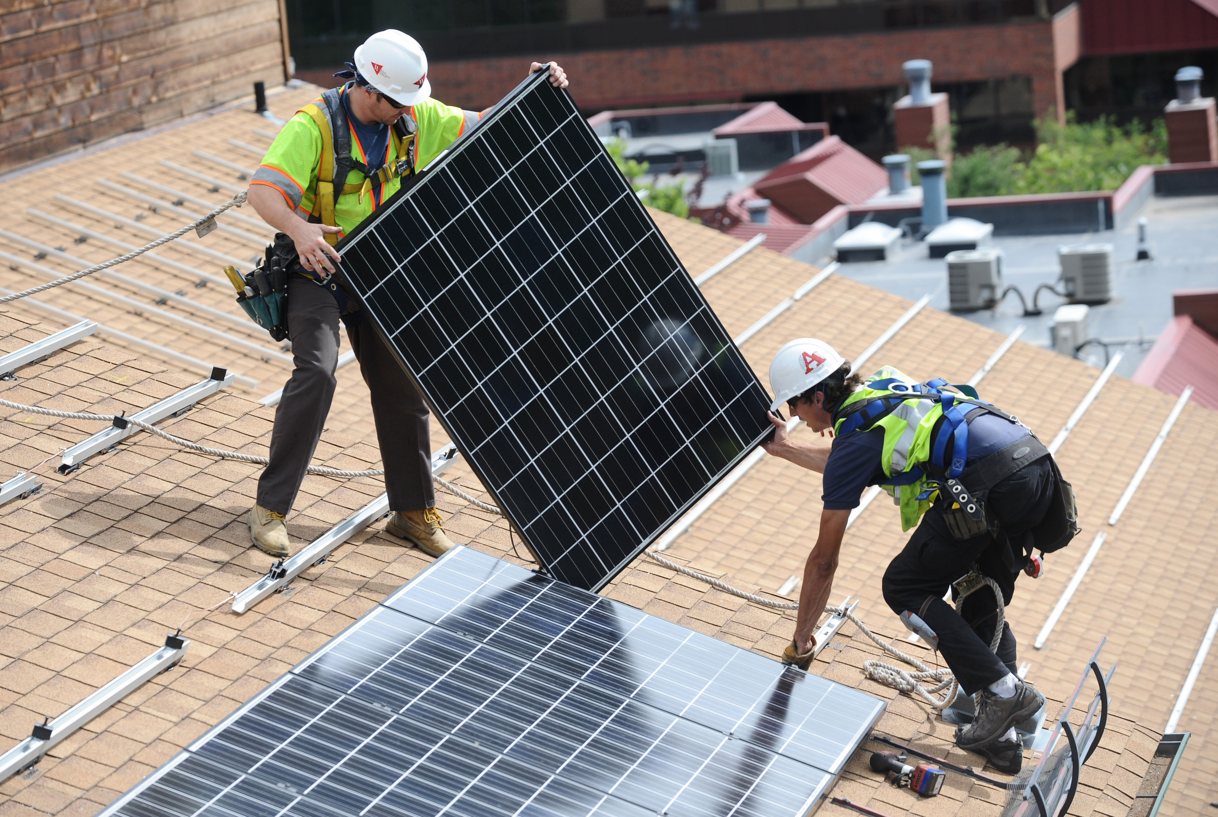 Crew installs solar panels on an apartment building.